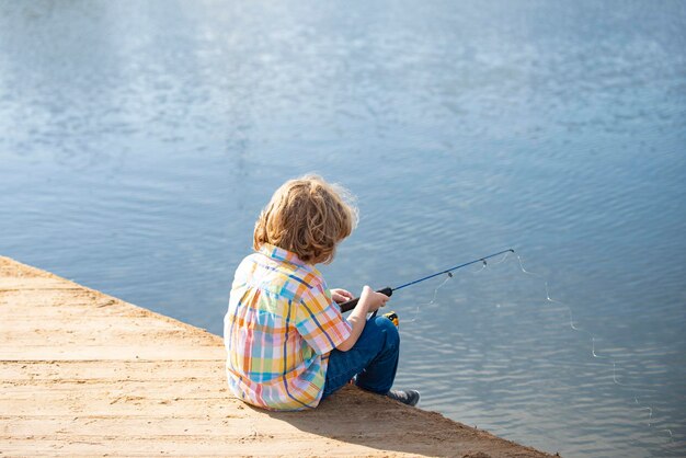 Child fishing young fisher boy with spinner at river portrait of excited boy fishing boy at jetty wi