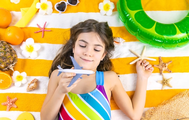 Child girl on a beach towel at the sea with an airplane. Selective focus. Kid,