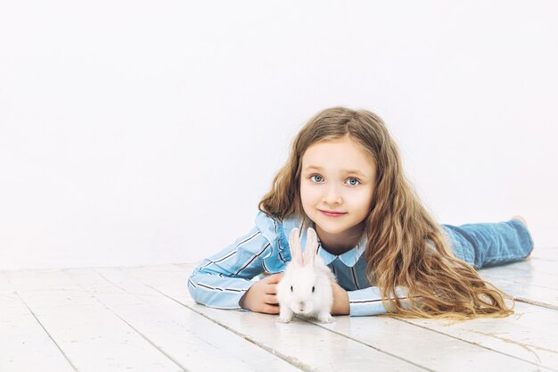 Child girl beautiful cute cheerful and happy with little animal rabbit on white wall background