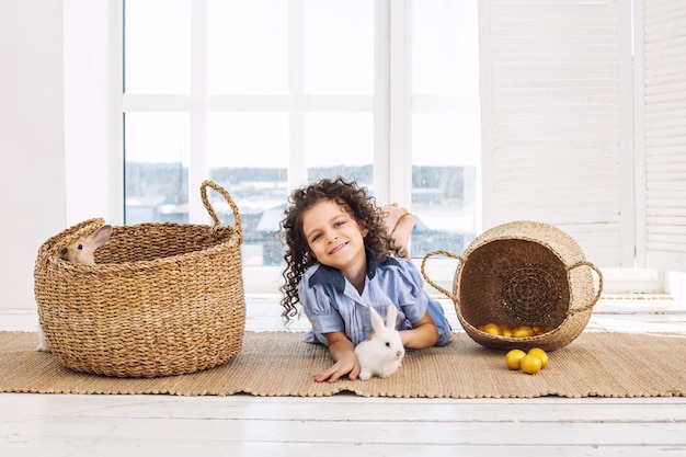 Child girl beautiful cute cheerful and happy with small animals rabbit and Easter eggs at home