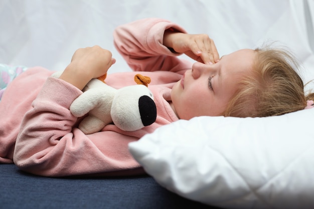 Child girl crying in bed hugging a toy