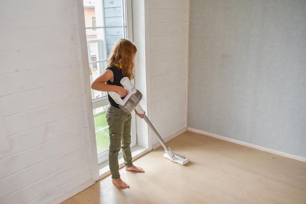 The child girl does vacuuming in the house photo without processing