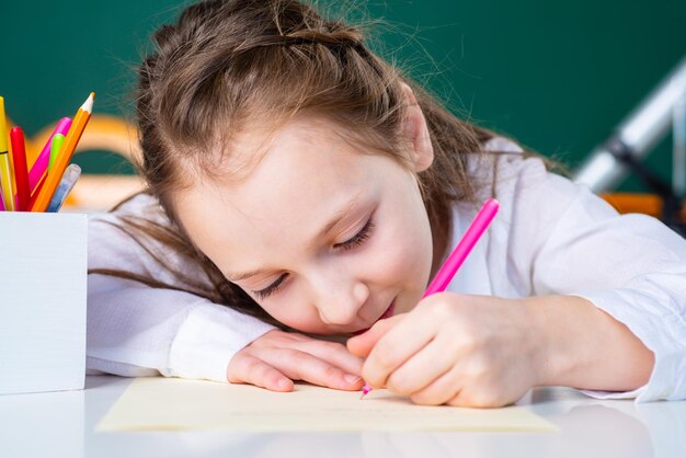 Child girl drawing picture in class close up face