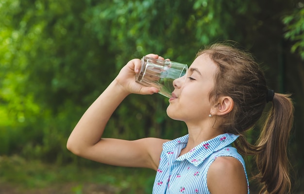 Child girl drinks water from a glass. 