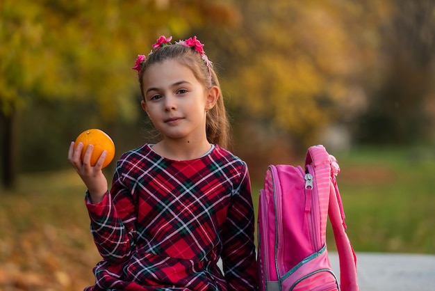 A child girl eating a healthy breakfast in the autumn park on school lunch.