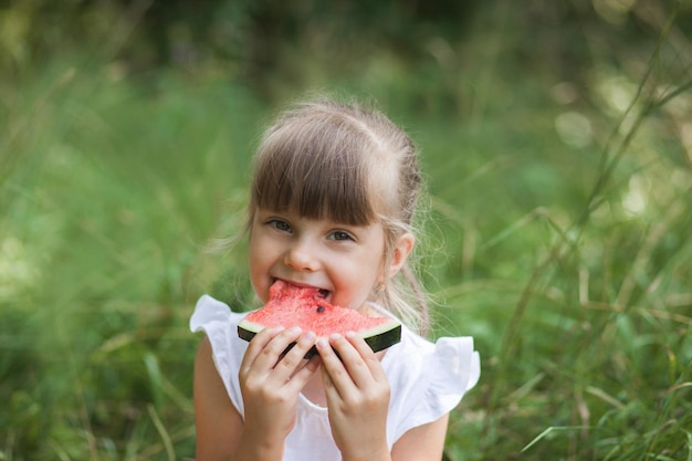 Child girl eating watermelon and smiling