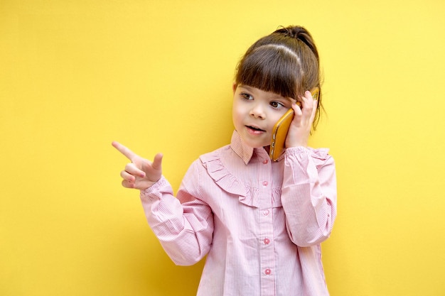 Child girl having serioys talk on phone gesturing explaining pointing finger at side isolated over y