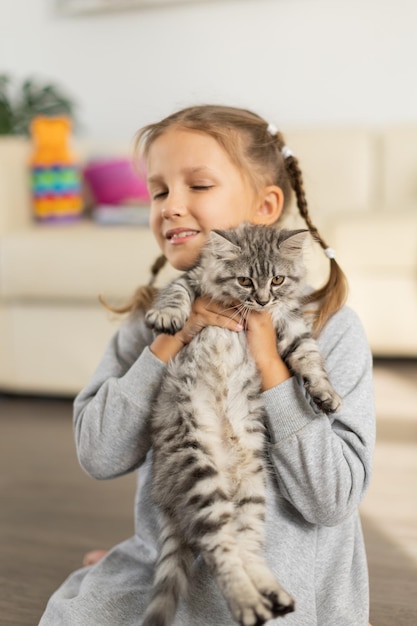 Child girl holding a fluffy kitten in her arms