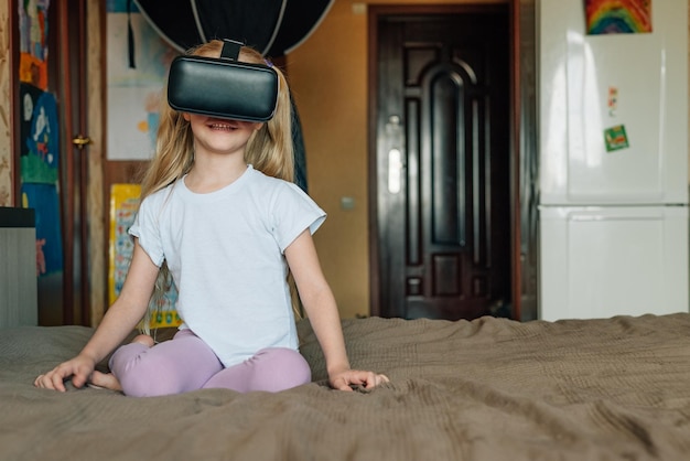 Child girl at home in virtual reality VR glasses watching video playing games modern children are well versed in technological innovations generation alpha