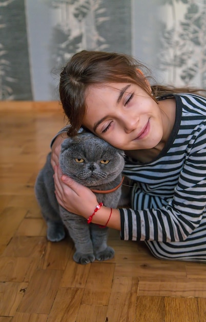 Child girl at home with a cat. Selective focus.