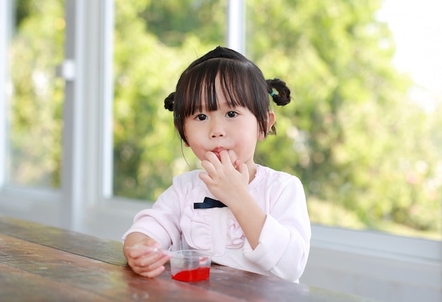 Child girl licking her fingers while eating.