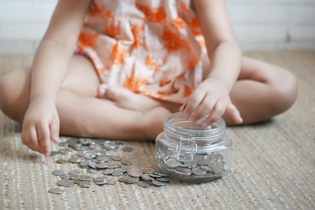 Child girl pile coin for saving sitting on floor