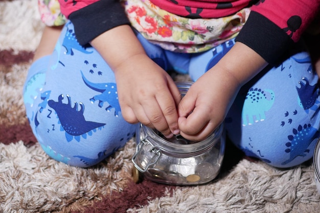 Child girl pile coin for saving sitting on floor