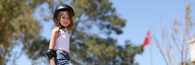 Child girl playing skateboarding in parking lot protective helmet elbow pads and wrist and knee