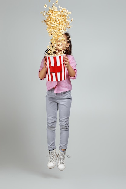 Photo child girl in redblue 3d glasses holding bucket with flying popcorn