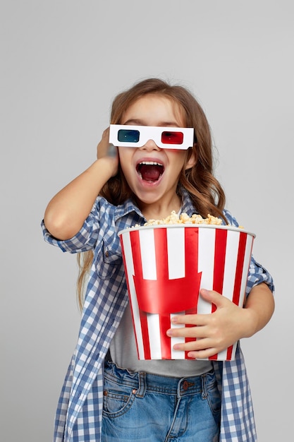 Child girl in redblue 3d glasses holding popcorn bucket