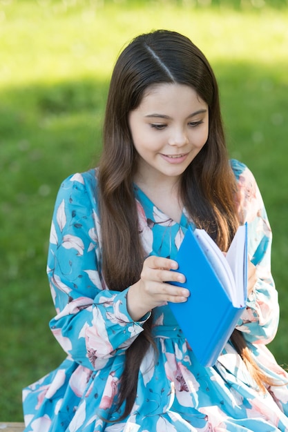 Child girl relaxing outdoors with book, new chapter concept.