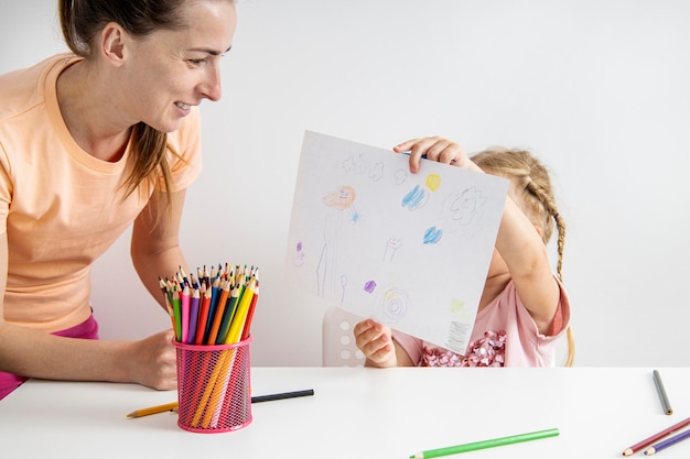 Child girl shows a drawn drawing with colored pencils on paper