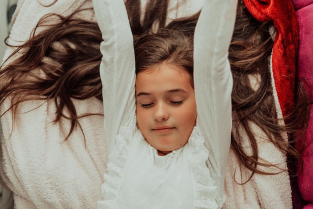 Child girl stretching while laying in bed after waking up