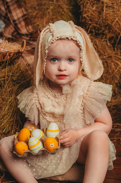 Child Girl wearing bunny ears and sitting with white ducklings on the wooden background