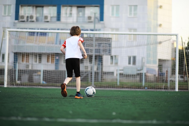 The child goes in for sports at the stadium The boy is training before playing football