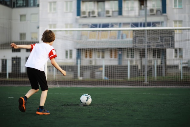 The child goes in for sports at the stadium The boy is training before playing football