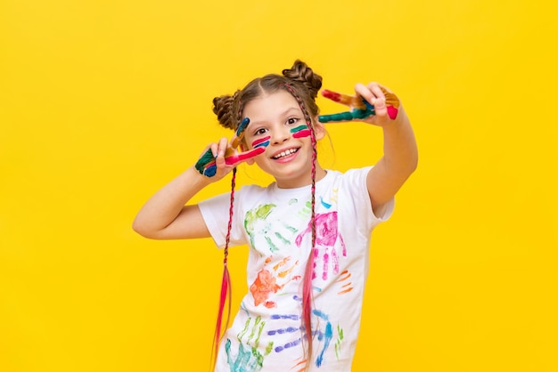 The child got dirty in multicolored paint A little girl with pigtails loves to paint Paint drawing lessons Children's creativity