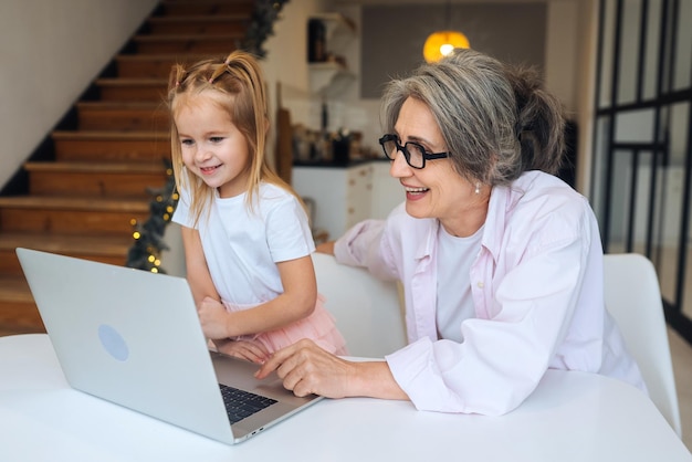 Child and granny looking at the camera with laptop at home