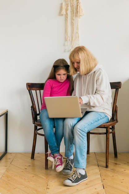 Child and granny using laptop in kitchen. Generation and family concept