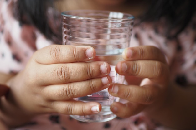 Child hand holding a glass of water