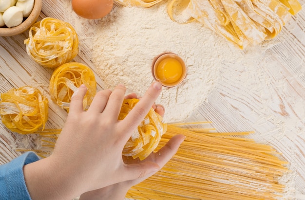 Child hand holding homemade pasta