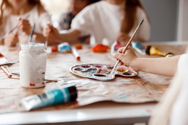 Photo child hand painting on paper with two classmate in the background