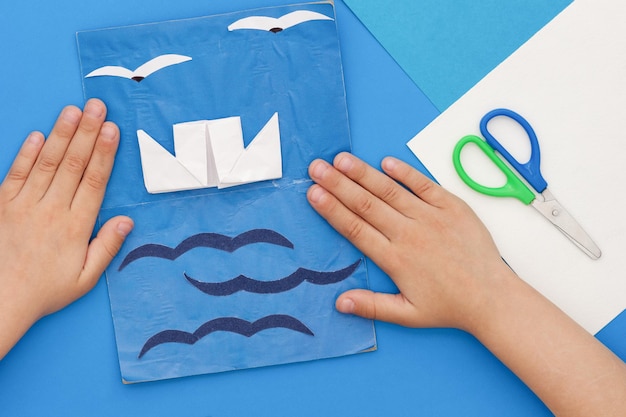 Child hands and card with ship sea and seagulls