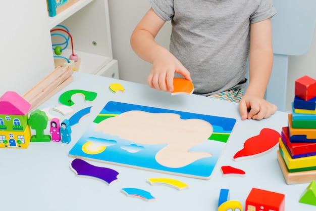 Child hands collect wooden puzzle