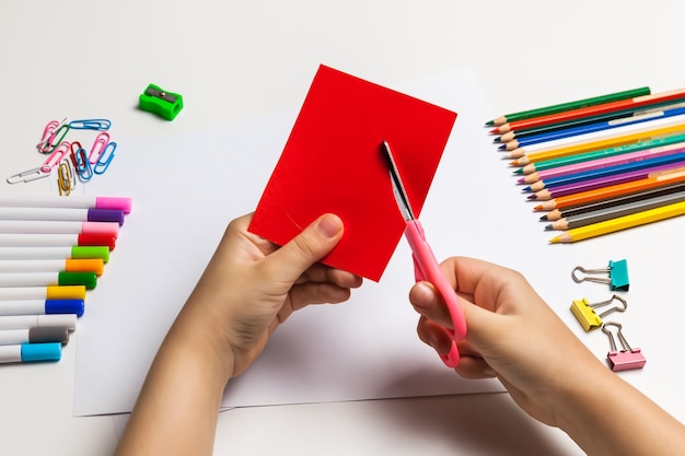 Child hands cutting a red heart out of paper