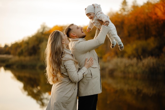 The child in the hands of the parents. Happy family walk in autumn in the park.