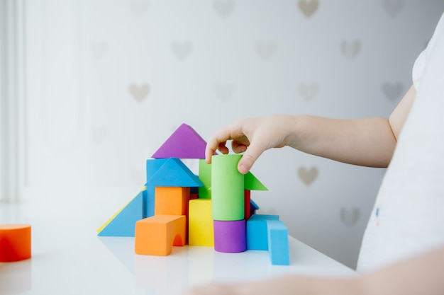 Child hands playing with colorful wooden bricks on the white tab