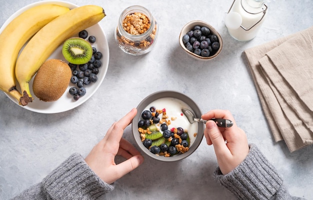 The child has breakfast with a hearty and healthy yogurt with granola and fresh fruits and berries Top view