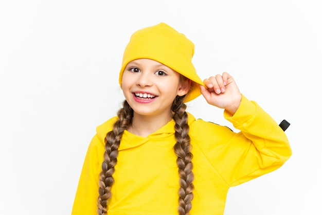 A child in a hat and a yellow tracksuit Closeup portrait of a smiling little girl