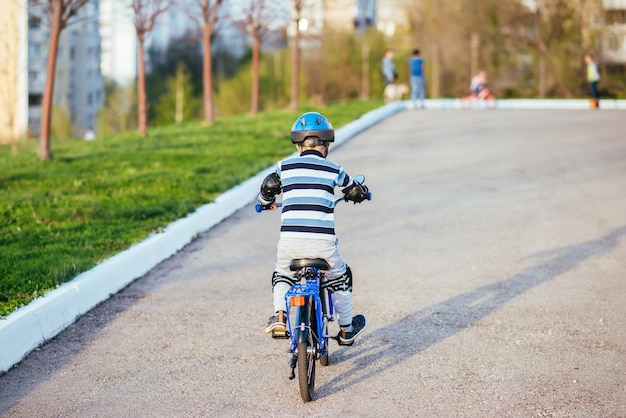 A child in a helmet and protection in a bike ride on nature in the spring