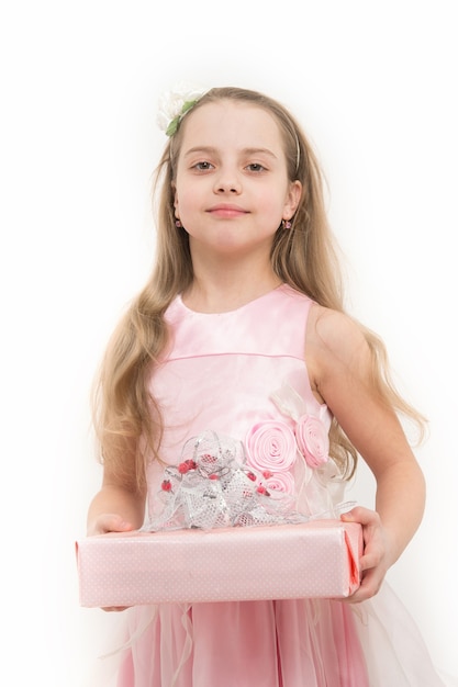 Child hold gift box isolated on white. Girl in pink dress with long blond hair. Holiday present and surprise. Birthday, anniversary celebration. Boxing day concept.