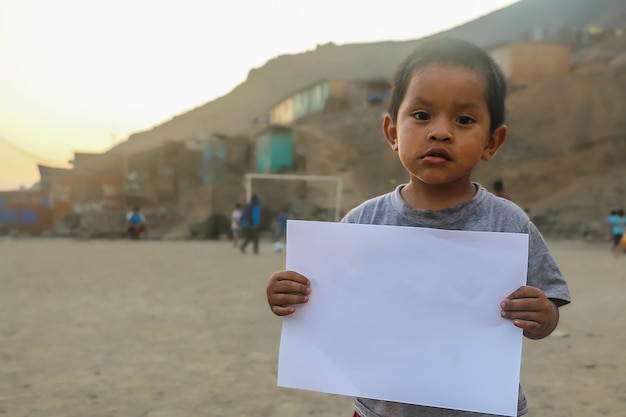 Child holding a blank sheet of paper to insert positive or motivational text or message.