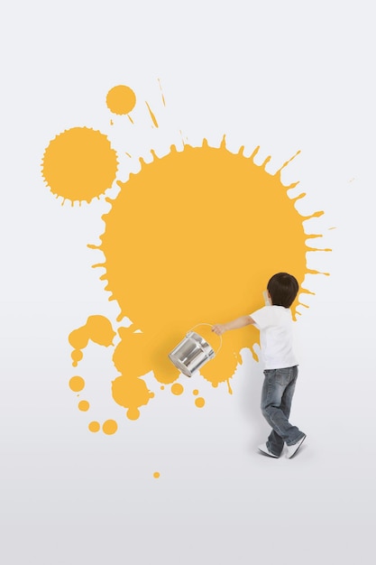 Child holding a can of paint spraying paint and coloring the wall