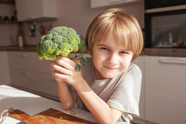 Child holding green broccoli Healthy food concept Child nutrition Fresh vegetables in the hands of a cheerful boy child