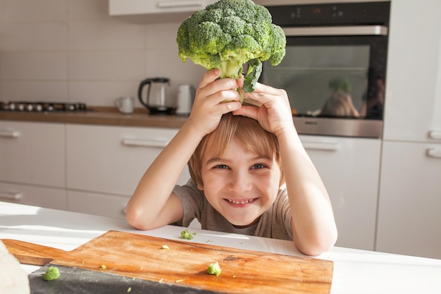 Child holding green broccoli Healthy food concept Child nutrition Fresh vegetables in the hands of a cheerful boy child