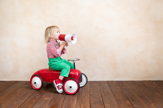 Photo child holding loudspeaker. kid shouting through vintage megaphone. business news concept