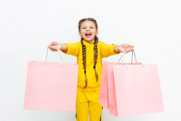 The child holds the bags with two hands Beautiful little girl after shopping with paper bags