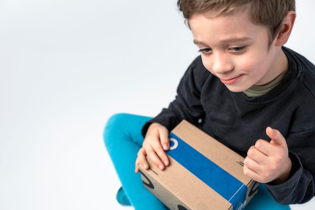 The child holds a cardboard box with a gift sent by the delivery service