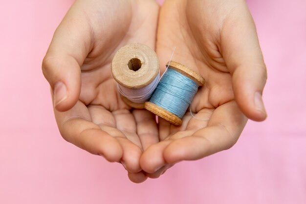 The child holds two spools of thread in his hands. Closeup, sewing and needlework concept for children.