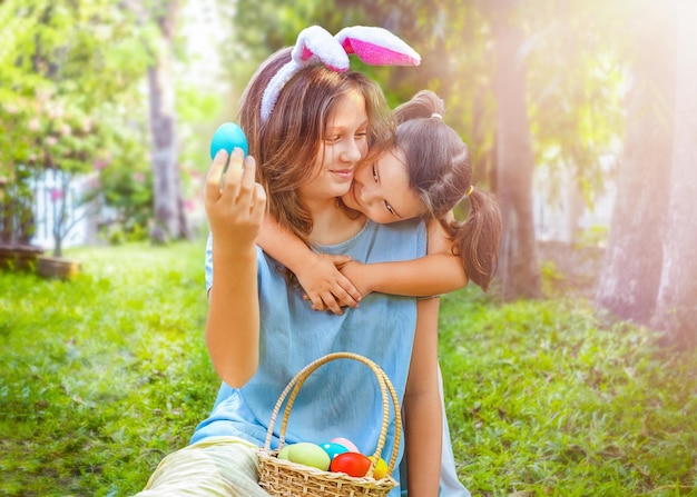 A child hugs a teenage girl and looks at Easter eggs in the backyard